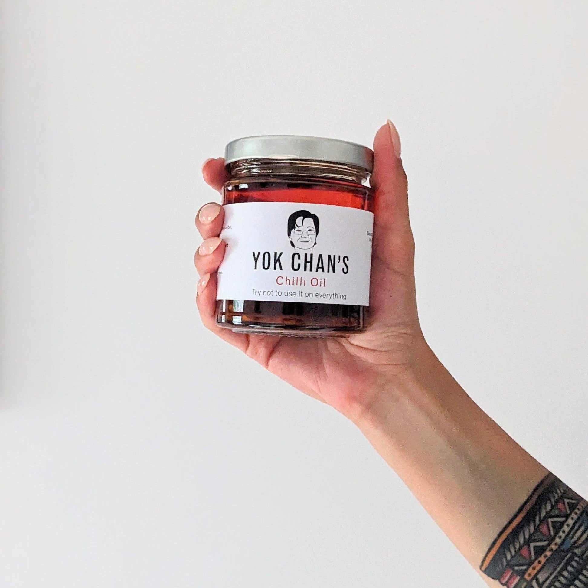 Hand holding a jar of 'Yok Chan's Chilli Oil' against a white background