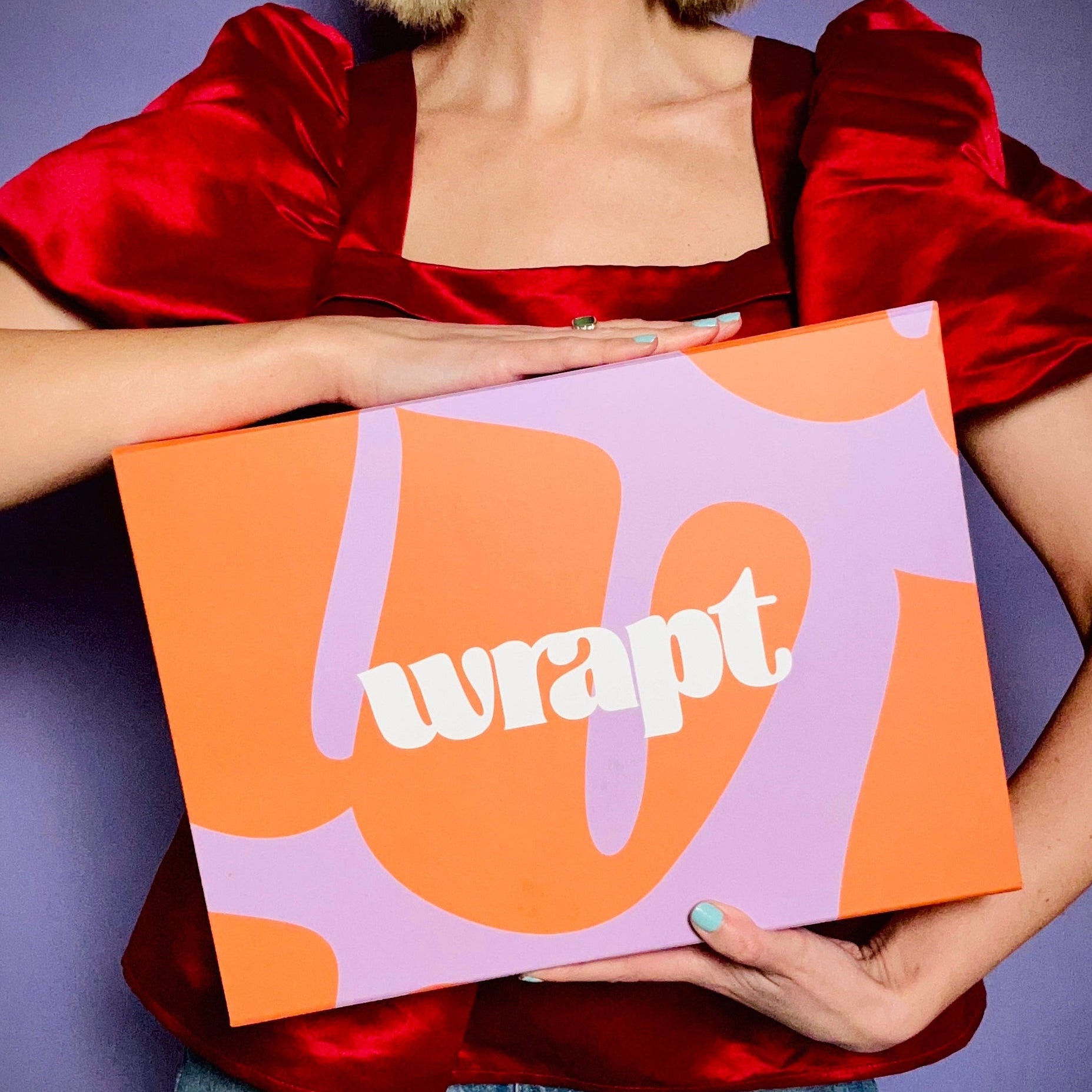 Person holding a colorful box with 'wrappt' branding against a purple background